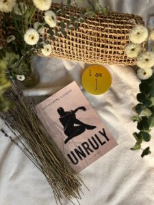 A book laying on a white cloth next to a basket and button that says "I am 1"